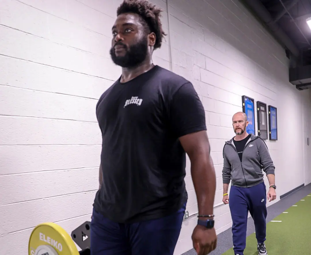 NFL offensive lineman Mike Onewenu performing a Single-Arm Farmer's Walk.